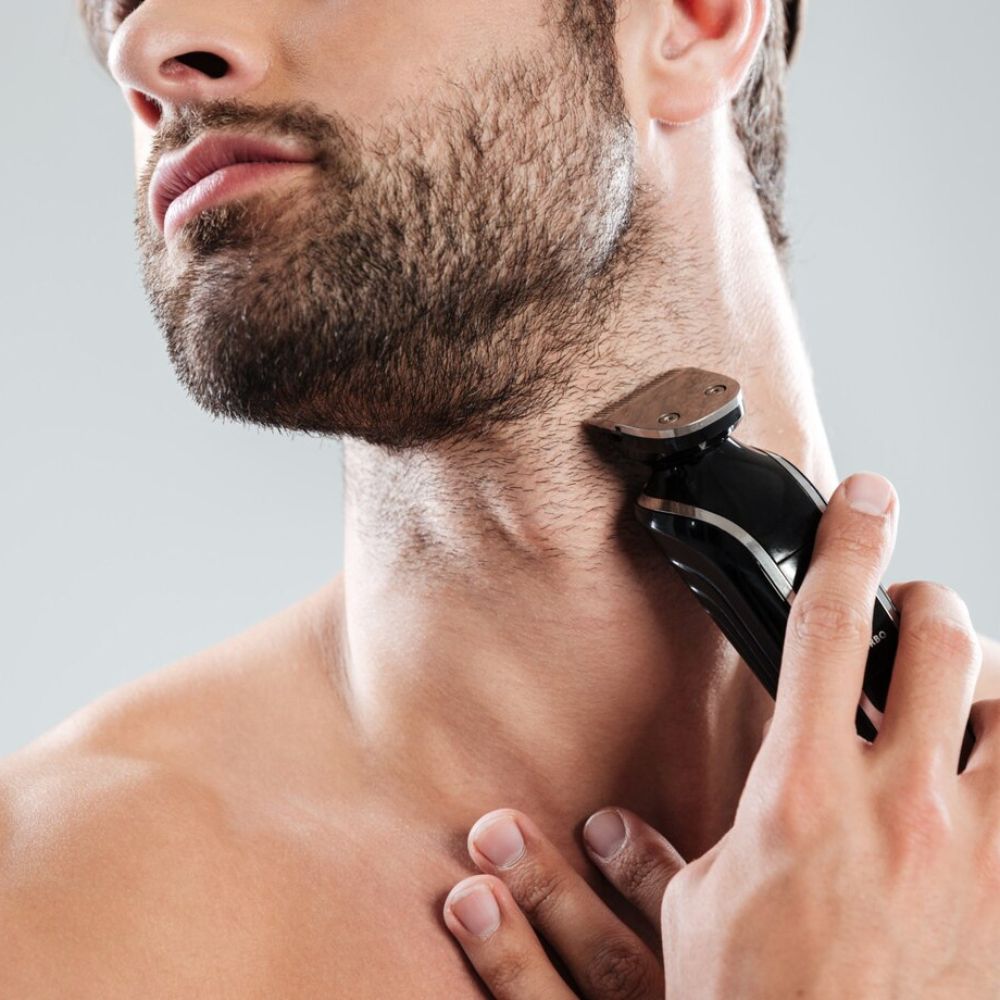 Man using an electric shaver on his neck against a gray background