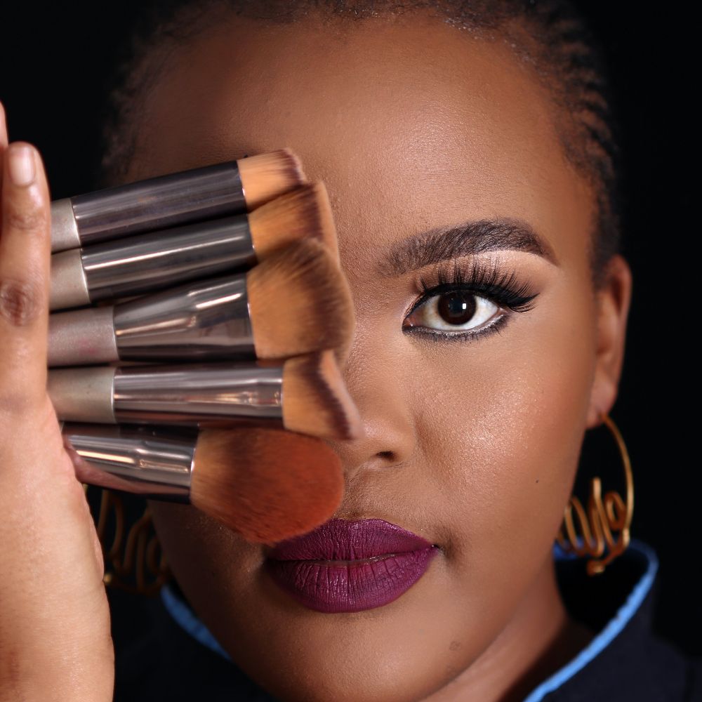 Woman holding makeup brushes with a dark background
